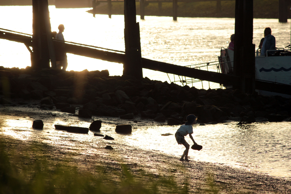 Kind spielt am Strand bei Sonnenuntergang